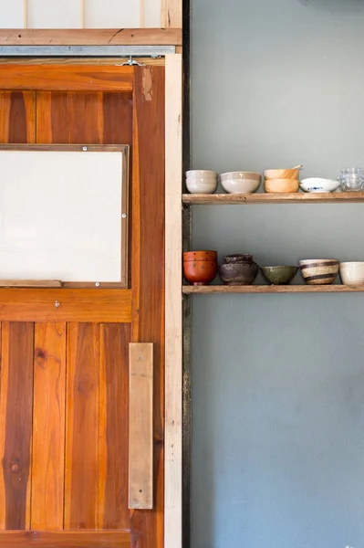 Drzwi drewniane z ceramicznym kubkiem na półce — Zdjęcie stockowe