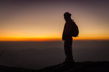 Gün batımı manzarasına bakan hafif siluet insan