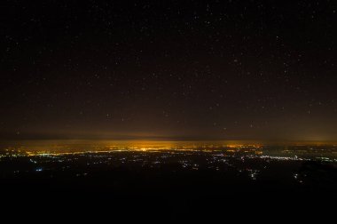 Gece gökyüzünde şehir ışıklarıyla yıldızlı manzara