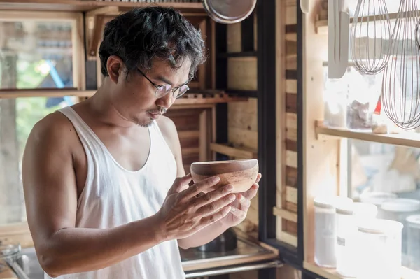 Um homem olhando uma xícara de madeira — Fotografia de Stock