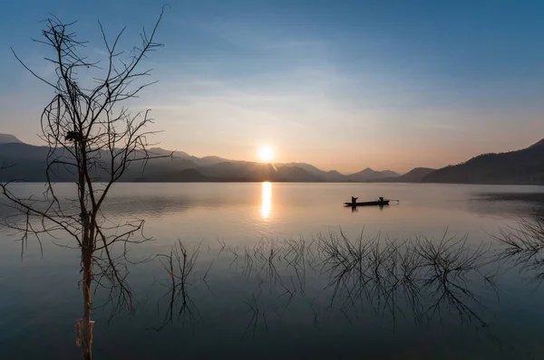 在有日出和山地的湖上运行的汽艇c 免版税图库图片