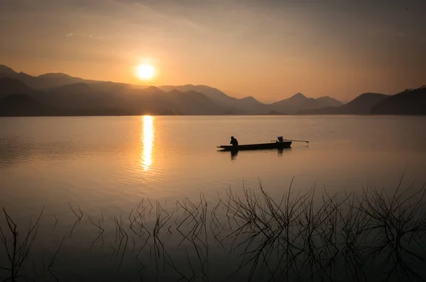 在有日出和山地的湖上运行的汽艇c 图库图片