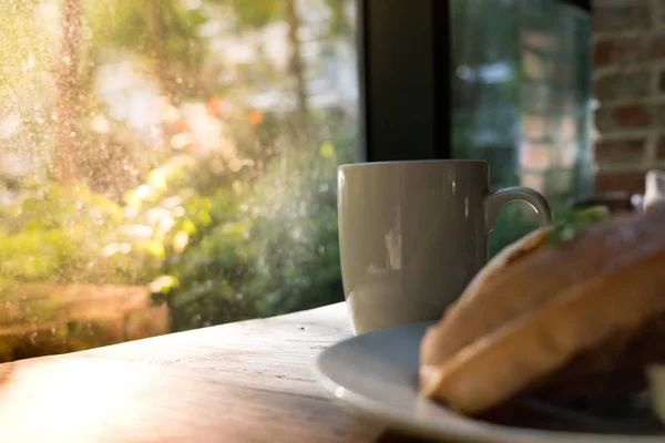 Belle matinée avec une tasse de café blanc avec gaufre floue sur table en bois — Photo