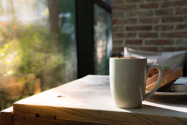 Heißer Mokkakaffee in weißer Tasse und verschwommene Waffel auf dem Holztisch — Stockfoto