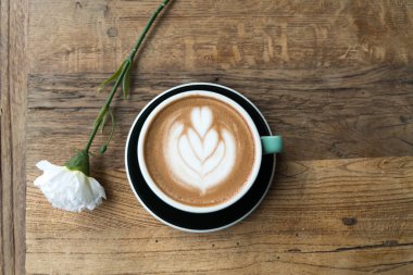 Sıcak mocha kahve veya capuchino ile kalp desen ve beyaz Karanfil ahşap masa üzerinde yeşil Kupası