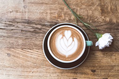 Sıcak mocha kahve veya capuchino ile kalp desen ve beyaz Karanfil ahşap masa üzerinde yeşil Kupası