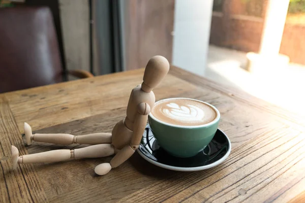 Café moca caliente o capuchino en la taza verde magra por el hombre de madera en la mesa de madera —  Fotos de Stock