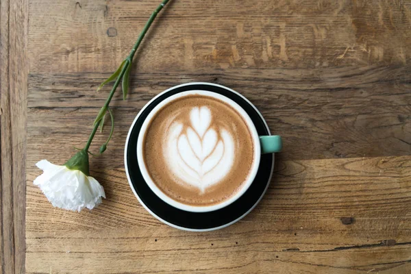 Sıcak mocha kahve veya capuchino ile kalp desen ve beyaz Karanfil ahşap masa üzerinde yeşil Kupası