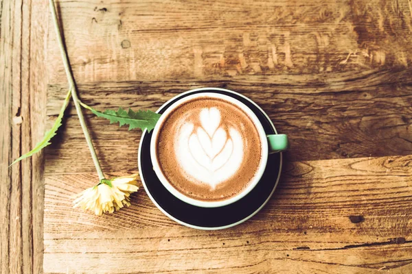 Café moka chaud ou capucin dans la tasse verte avec motif coeur et œillet blanc sur la table en bois — Photo