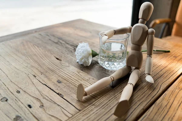 Un hombre de madera está sentado y poner el brazo en el vaso de agua —  Fotos de Stock