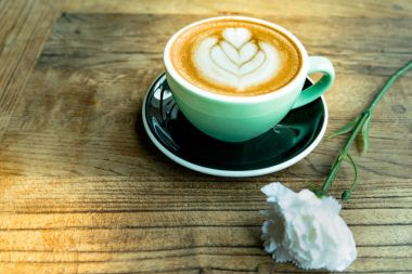 Sıcak mocha kahve ya da capuchino kalp desen ve ahşap masa üzerinde beyaz Karanfil çiçek