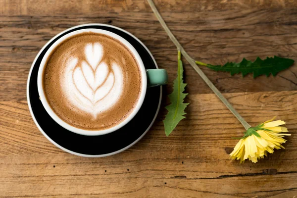 Sıcak mocha kahve veya capuchino ile kalp desen ve sarı çiçek ve beyaz Karanfil ahşap tablo