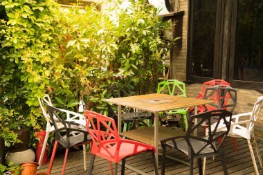 Açık havada masa ve renkli sandalyeler bir köşesinde