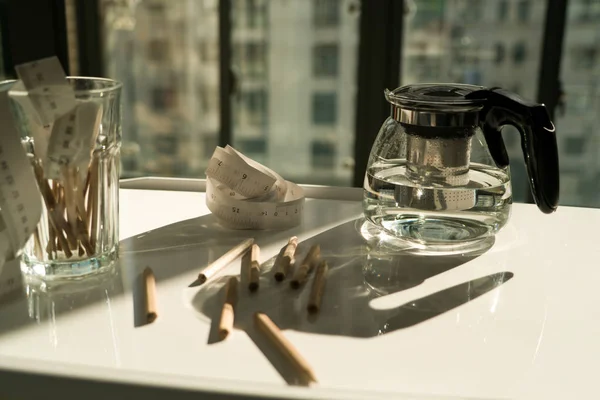 Panela de chá com fita métrica e lápis na mesa de trabalho, conceito de trabalho e descanso — Fotografia de Stock