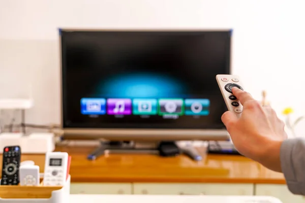 a women hand hold the remote control of the TV box in the living room