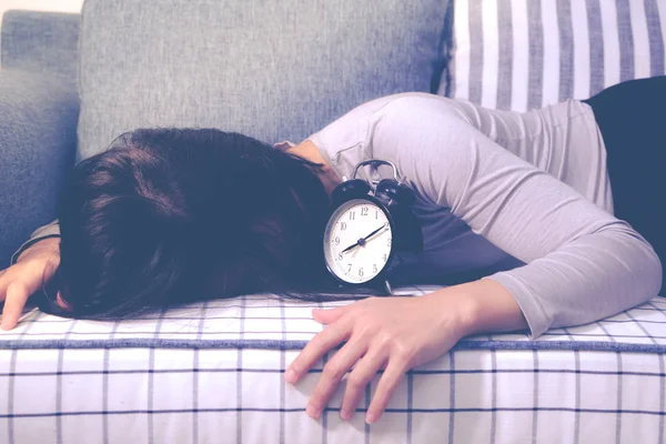 Femmes paresseuses est allongé sur le canapé après l'alarme d'horloge, réveil tardif concept de style de vie — Photo