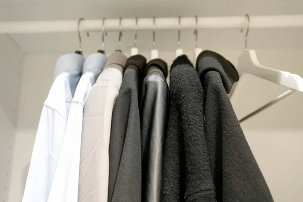 Rad av män och kvinnor skjortor på galgen, hängande i garderoben — Stockfoto