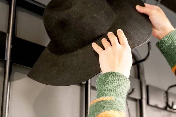 Женщины, вешающие черную шляпу на вешалку — стоковое фото