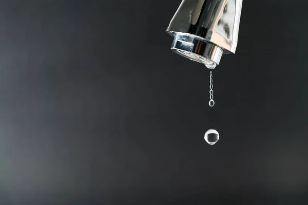 Капля воды на кране с черным фоном, концепция Всемирного дня воды с копировальным пространством — стоковое фото