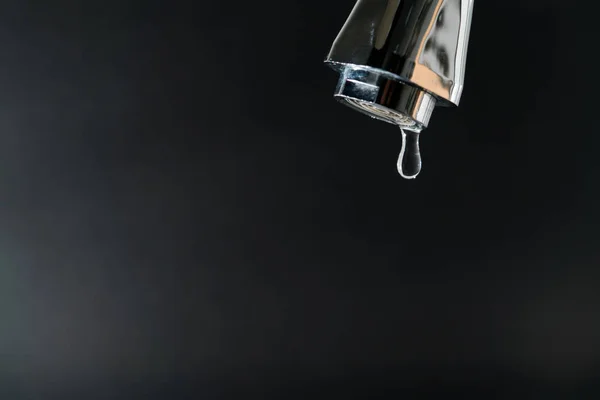 Капля воды на кране с черным фоном, концепция Всемирного дня воды с копировальным пространством — стоковое фото