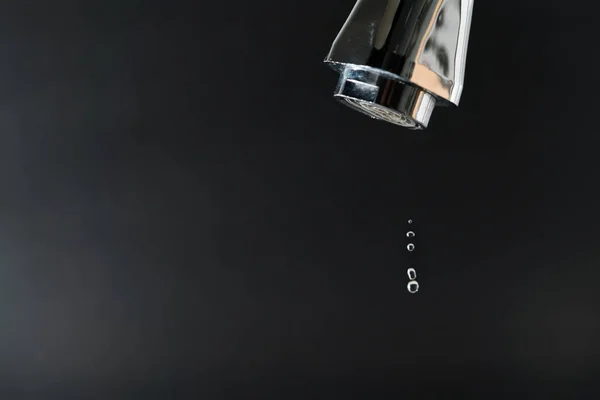 Капля воды на кране с черным фоном, концепция Всемирного дня воды — стоковое фото