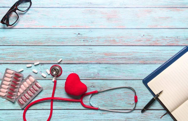 Hälsovård och medicinska begrepp röd stetoskop och medicin på den blå trä bakgrunden — Stockfoto