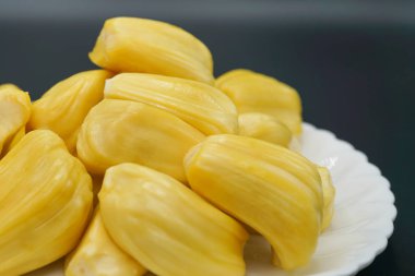 Beyaz tabakta taze meyve dilimleri. Tatlı sarı meyveler olgunlaşmış. Vejetaryen, vejetaryen, çiğ yemek. Egzotik tropikal meyve - izole