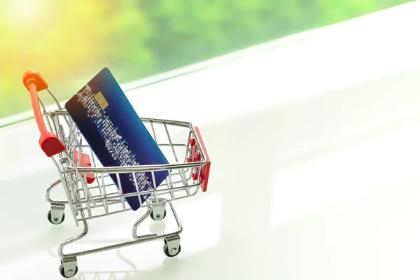 Credit card op het winkelwagentje van de kar op witte tafel met een groene achtergrond — Stockfoto