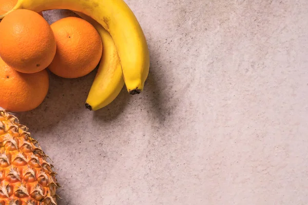 Tropiska och säsongsbetonade sommaren frukter. Ananas apelsiner och bananer ordnade i hörnet av bakgrunder, hälsosam livsstil. Flat Lay — Stockfoto
