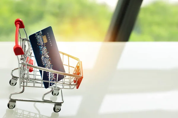 Credit card op het winkelwagentje van de kar op witte tafel met een groene achtergrond — Stockfoto