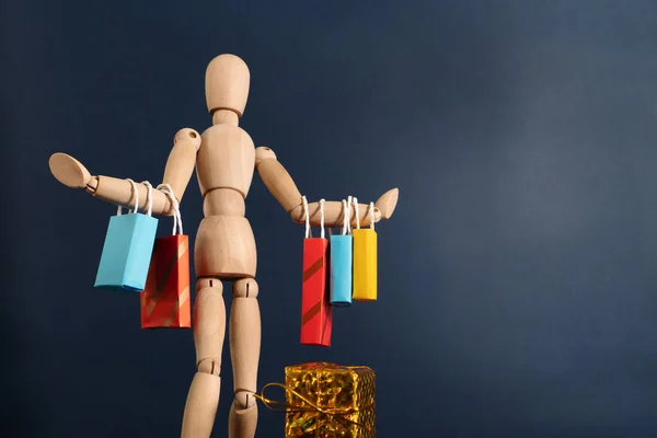Vrolijk gelukkig shopaholic houten pop met veel boodschappentassen aan de arm — Stockfoto
