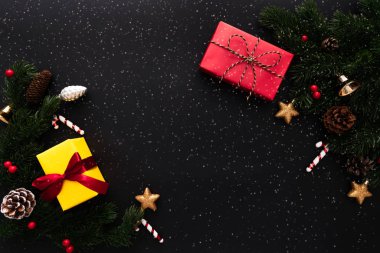 Noel hediyesi kutusu ve siyah arka planda Noel süslemesi olan çam ağacı.