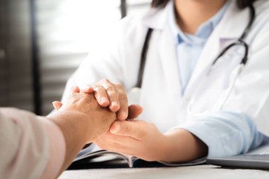 Doktor el ele tutuşup yaşlı kadın hastayı tutuyor.