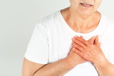 Beyaz arka planda göğsünü tutan yaşlı bir kadın kalp krizi geçirdi.