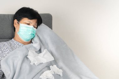 Kirli mendilli bir maske takan hasta bir son sınıf öğrencisi. Battaniye giymiş hasta adam, yün kanepeye uzan.