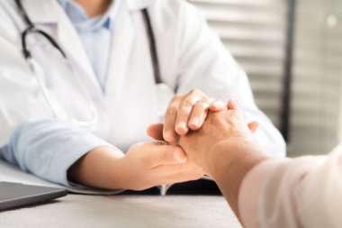 Doktor el ele tutuşup yaşlı kadın hastayı tutuyor.