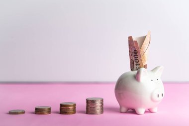 Para biriktirme ve bağış konsepti, pembe masadaki şirin beyaz domuz kumbarasına para