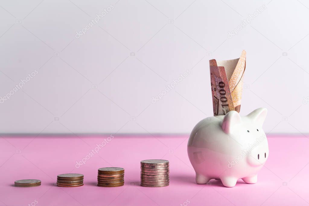 Money saving and donation concept, money on cute white piggy bank on pink table