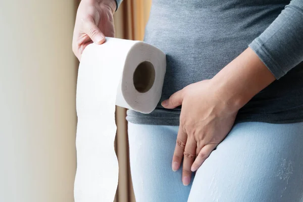 Disorder, Diarrhea, incontinence. Healthcare concept. Woman hand holding her crotch lower abdomen and tissue or toilet paper roll. — Stock Image Disorder Diarrhea Incontinence Healthcare Concept Woman Hand Holding Her Crotch Stock Photo
