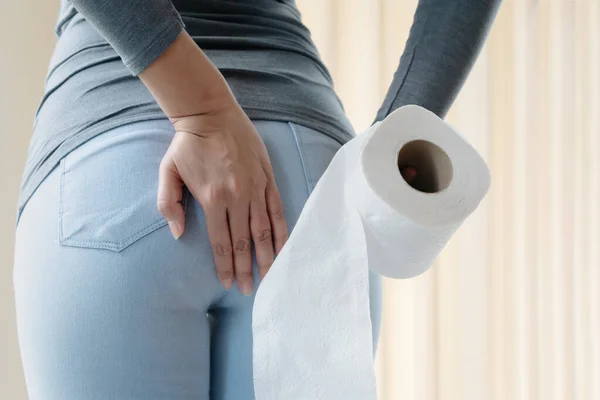 Disorder, Diarrhea, incontinence. Healthcare concept. Woman hand holding her bottom and tissue or toilet paper roll. — Stock Image Disorder Diarrhea Incontinence Healthcare Concept Woman Hand Holding Her Bottom Stock Picture