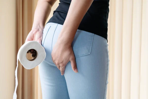 Disorder, Diarrhea, incontinence. Healthcare concept. Woman hand holding her bottom and tissue or toilet paper roll. — Stock Image Disorder Diarrhea Incontinence Healthcare Concept Woman Hand Holding Her Bottom Stock Image
