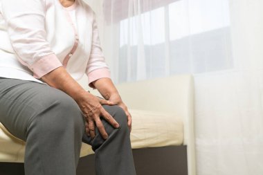 Evde yaşlı bir kadının diz ağrısı, yaşlı bir kadının sağlık sorunu.