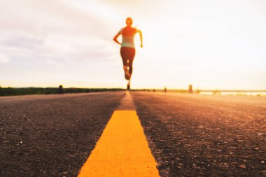 Gün batımında koşan bir sporcu maraton ve spor için antrenman yapıyor. Dışarıda egzersiz yapan bir kadının hareket bulanıklığı.
