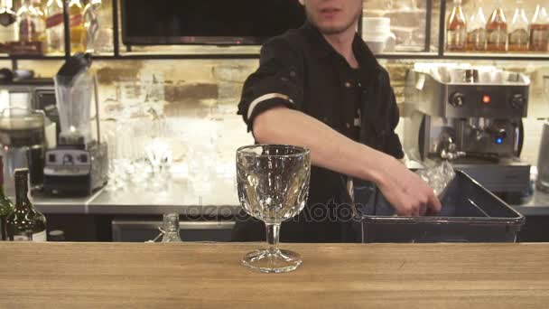 Bartendern håller isen kuben cocktailglas. Bartender förbereda alkoholhaltiga drinkar. närbild. — Stockvideo