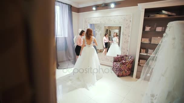 Feminino tentando em vestido de noiva em uma loja com mulheres assistente . — Vídeo de Stock