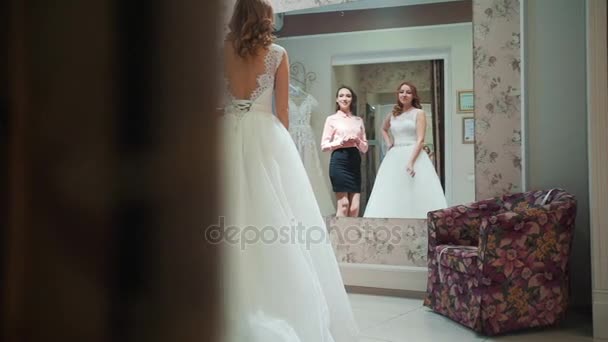 Donna che prova l'abito da sposa in un negozio con le donne assistente . — Video Stock