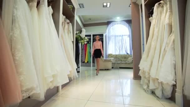 Smiling pretty bride chooses wedding gown at bridal boutique — Stock Video