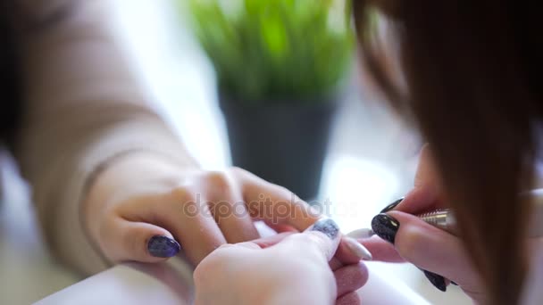 Primer plano de manicura de hardware en un salón de belleza. Manicura está aplicando taladro de lima de uñas eléctrica a la manicura en los dedos femeninos . — Vídeos de Stock