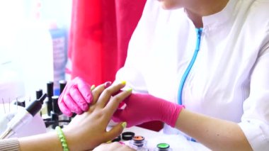 Bir tırnak salonda kadın tırnak tırnak cilası uygulayarak bir güzellik closeup çekim. Bir kadın elinin sarı oje ile manikür sonra yakın çekim.