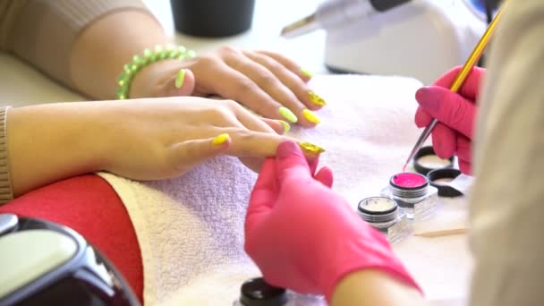 Primo piano di un estetista che applica lo smalto per unghie femminili in un salone di bellezza. Primo piano di una mano di donna con smalto giallo dopo la manicure . — Video Stock